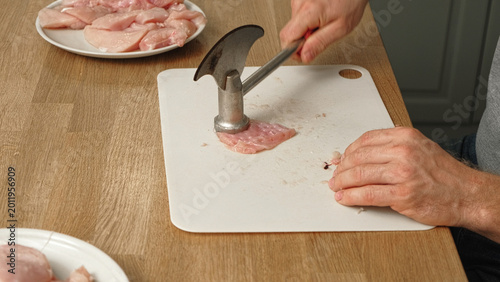 Tableau sur toile Person using meat tenderizer on raw chicken