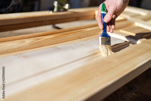 Cuadro en lienzo Applying protective varnish on wooden door with paint brush