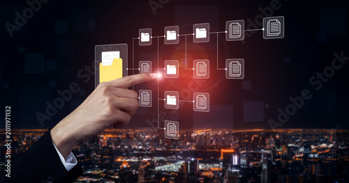 Valokuva A professional hand interacts with a virtual display of file sharing and data management against a vibrant city skyline at night, symbolizing innovation in technology and organization