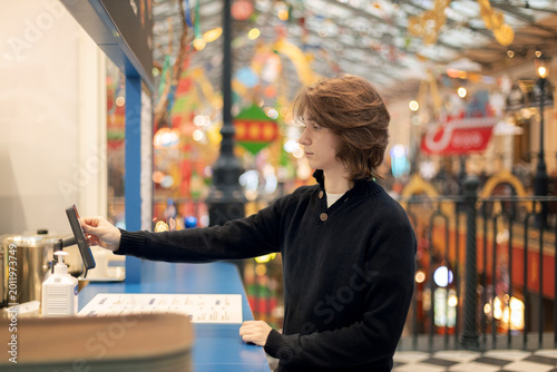 A young man paying for an order at a food court, fast food in a modern shopping  mall, lunch break,