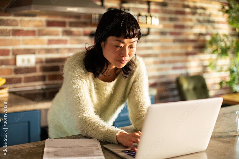 © Davor - Woman managing finances on laptop in home kitchen © Davor - Woman managing finances on laptop in home kitchen