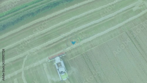 Combine harvester entering bottom, cutting swaths, turning, showing UI icons for harvest monitoring
