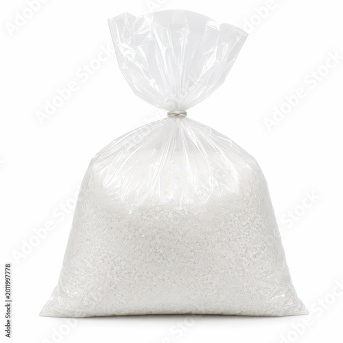 A bag filled with white rice sits in a kitchen. This white rice is ready to be cooked for meals. The bag is clear and shows the rice inside.