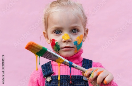 Girl with a brush and bright paint on her face, photorealistic portrait, soft diffused lighting