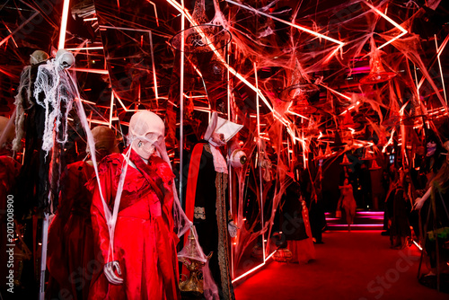 The atmospheric photography from the Halloween-themed event features a dramatic Halloween-inspired set, framed by spooky costumes, faux spider webs and mystical red lighting.