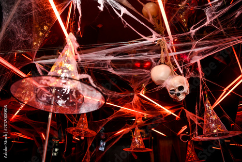 The atmospheric photography from the Halloween-themed event features a dramatic Halloween-inspired set, framed by spooky costumes, faux spider webs and mystical red lighting.
