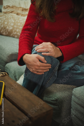 Fotografía Anonymous young woman at home holding her knee in pain