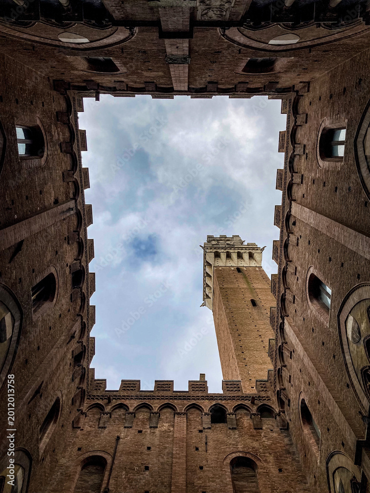 Naklejka premium Low angle view of Torre del Mangia tower from the courtyard of Palazzo Pubblico in Siena, Tuscany.