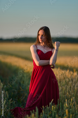 Woman rye field red dress. Happy woman in a long red dress in a beautiful cornfield. Old caste ruins in the background