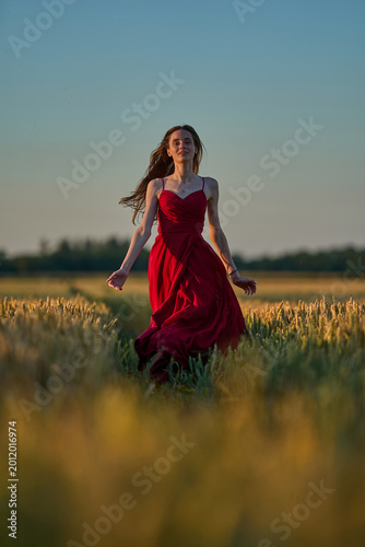 Woman rye field red dress. Happy woman in a long red dress in a beautiful cornfield. Old caste ruins in the background