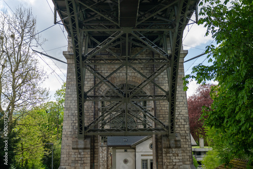 Photography View from beneath a steel girder bridge with stone supports and trees in Bern, Switzerland