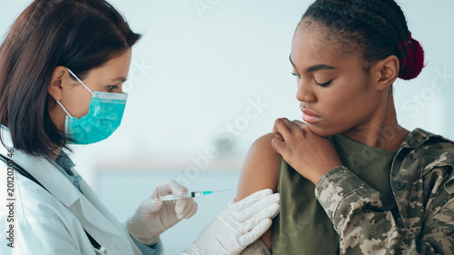 Obraz na plátně A healthcare worker is administering a vaccine to a soldier