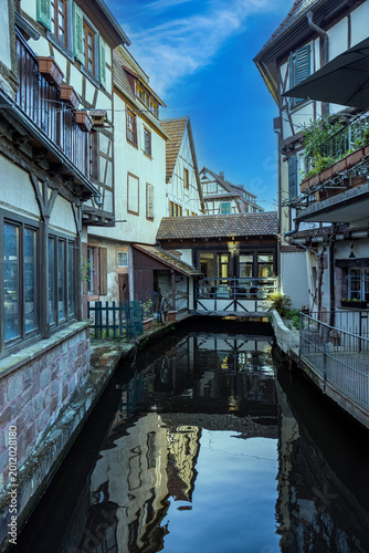 Traditional half-timbered houses reflected in a narrow canal in Wissembourg, France
