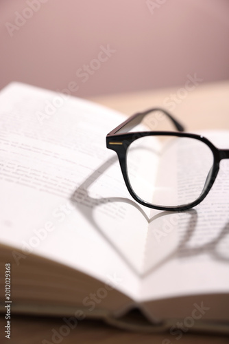 Konstfotografi Stylish glasses and book on table, closeup