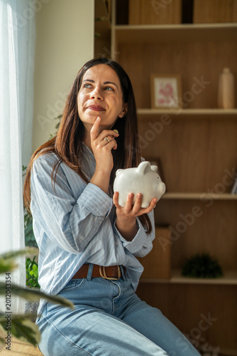 Foto Woman thinking about financial future holding piggy bank