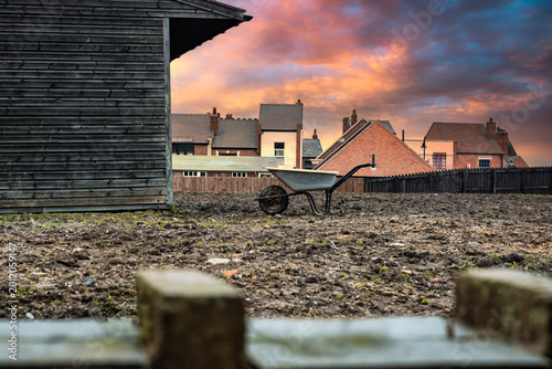 2026-03-07 OUTDOOR SCENE OF A PLOWED BACKYARD WITH A WHEEL BARROW AND THE TOPS OF A ROW OF OLD HISTORIC BUILDING IN THE BLACK COUNTRY OUTSIDE OF BIRMINGHAM ENGLAND