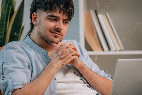 Quadro su tela young man looking at laptop suspiciously, hesitant