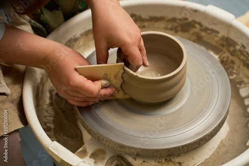 Tableau sur toile Traditional ceramic vase making with an artisan shaping tall clay on a pottery wheel