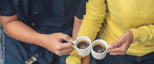 Banner Close up Hands holding coffee cup. Couple lover drinking black cup of coffee together. Banner Top view hands two people happy cafe coffee shop. Espresso shot with copy space