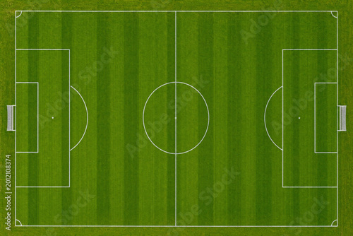 Slika na platnu Aerial top down view of a green soccer field with white markings and goals, foot