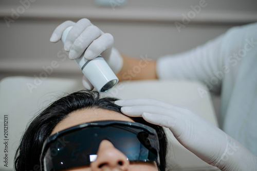 Bild auf Leinwand Female specialist using scalp therapy device on male client during aesthetic hair treatment session