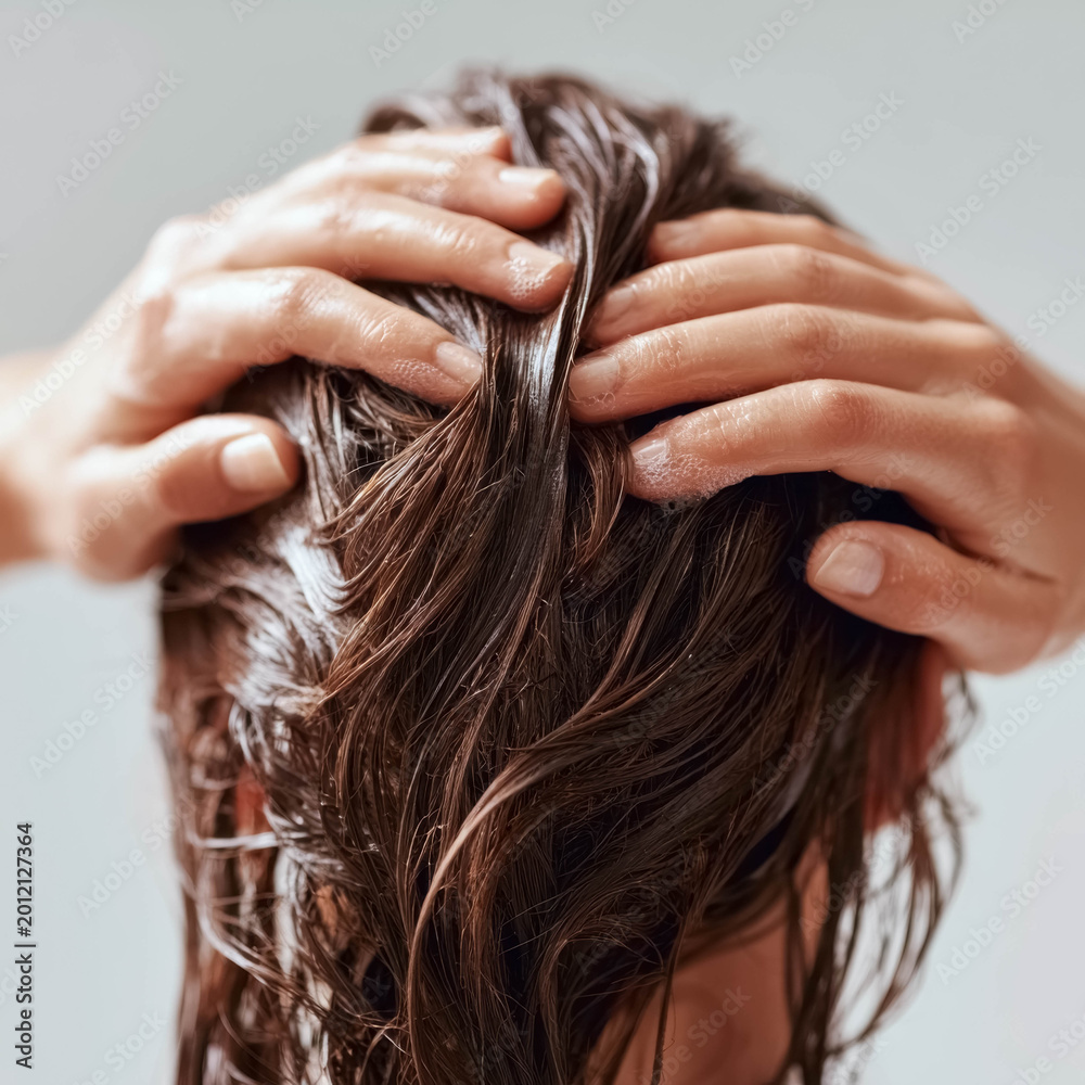 Naklejka premium Close up of person applying nourishing hair treatment cream onto wet hair during care routine