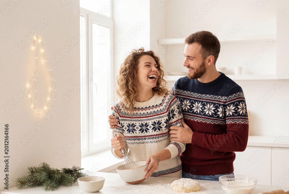 Fototapeta premium Cheerful young couple playfully cooking holiday treats in modern kitchen