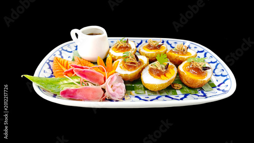 Fotografie Authentic Thai son-in-law eggs featuring crispy fried eggs and rich tamarind glaze, garnished with chili and fried shallots on black background