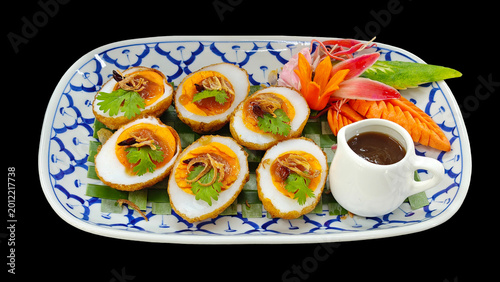 Tableau sur toile Elegant Thai appetizer of deep-fried hard-boiled eggs with savory tamarind glaze, perfect  on black background