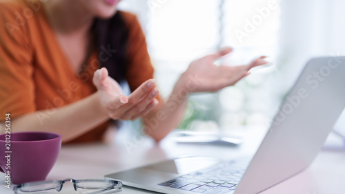 Fotografie remote working women using laptop computer hand gesture explaining business conc