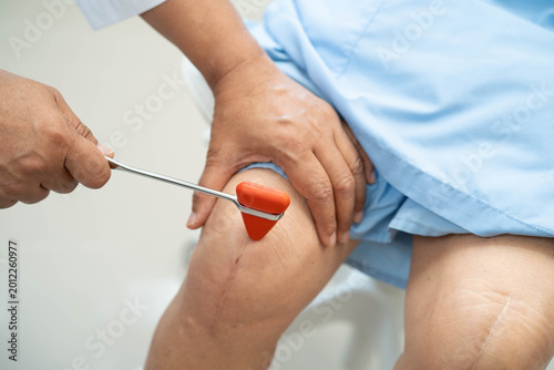Obraz na płótnie Asian doctor knock on knee reflex nerve for check and treatment senior patient in hospital