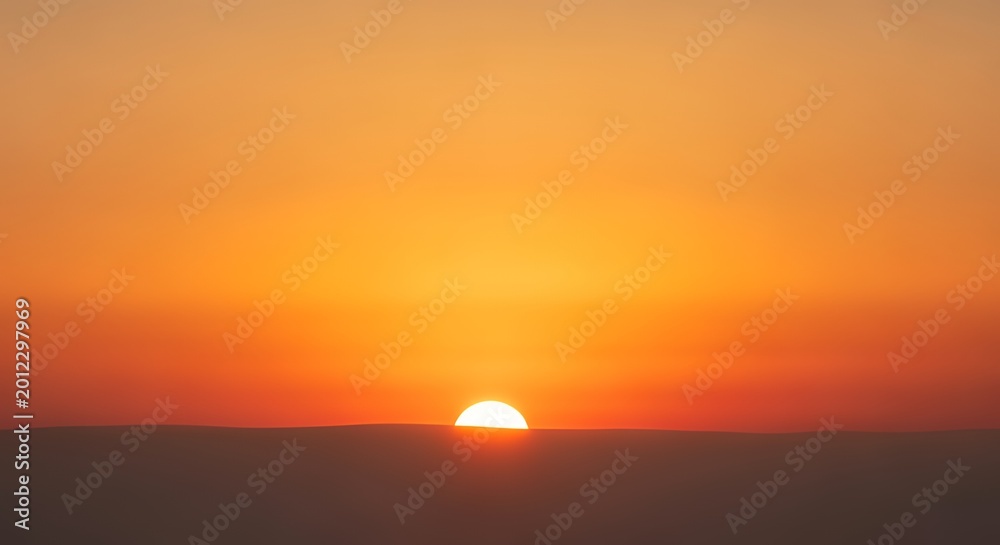 Fototapeta premium Sunset over horizon with setting sun in warm orange sky