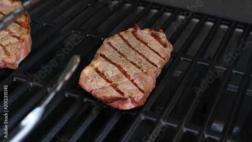 Tableau sur toile Close-up of Beef Steaks with Grill Marks Cooking on a Barbecue