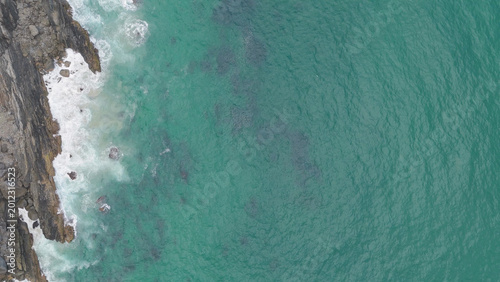 Fotografie Aerial Top Down View of Turquoise Ocean Crashing Against Byron Bay Cliffs