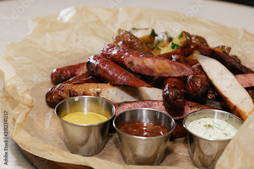 Foto Assorted grilled sausages with various dipping sauces on parchment