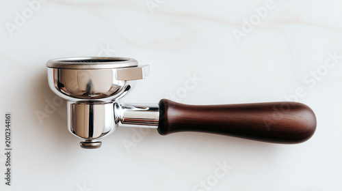 Professional chrome-plated espresso portafilter with an elegant dark wood handle lying on a clean white marble background, ideal for coffee shop branding and barista tool displays