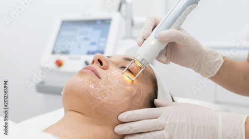 Calm woman receiving advanced skincare laser therapy on her face. professional beauty treatment for rejuvenation in modern dermatology clinic with specialized equipment