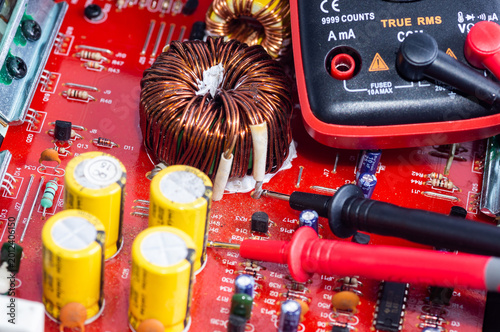 Slika na platnu A multimeter with test probes and a circuit board lie on a white background