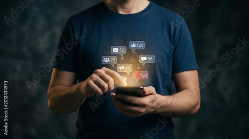 Digital Connection: An individual interacts with social media icons on a smartphone, highlighting the blend of technology and human interaction.