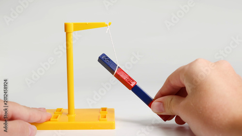 Obraz na płótnie Hands Demonstrating Magnetic Attraction and Repulsion Using Suspended Bar Magnet