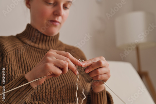 Photos A woman sits quietly at home and uses her hands to knit with a pair of needles