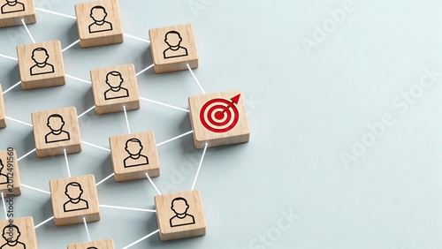 Wooden blocks with human icons connected by white lines to a red target symbol on a light blue background representing business networking recruitment strategy and goal achievement