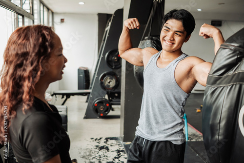 Foto Confident muscular man flexing his biceps to an impressed and amazed woman insid