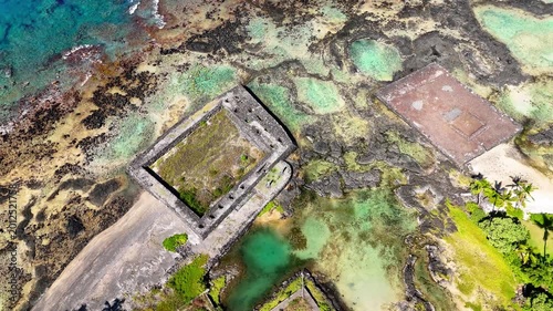 Aerial view of the ancient stone heiau ruins at Kahaluu Beach Park with turquoise coastal waters and volcanic rock formations in Kailua-Kona, Hawaii, United States.