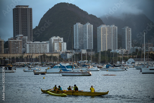Fényképezés Outrigger Canoe Paddling through Guanabara Bay with Botafogo Skyline in Rio de J