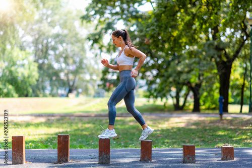 Foto Woman moving quickly across wooden blocks, improving coordination, balance and speed in outdoor fitness training