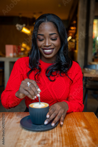 Foto Woman enjoying coffee, stirring latte in a cafe