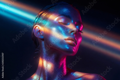 Subject: A woman with shimmering skin. Action: Illuminated by vibrant light, she appears to be meditating or lost in thought. Setting: A dark, abstract space with neon lighting.