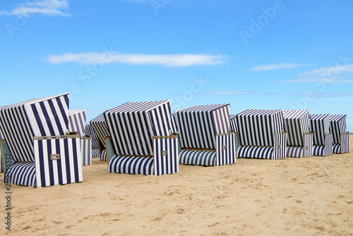 Fotografie Striped beach chairs from the wind strandkorb on the background of sand and blue sky