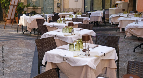 Elegant outdoor restaurant terrace with fully set tables. Refined dining atmosphere for hospitality, travel, and leisure marketing.